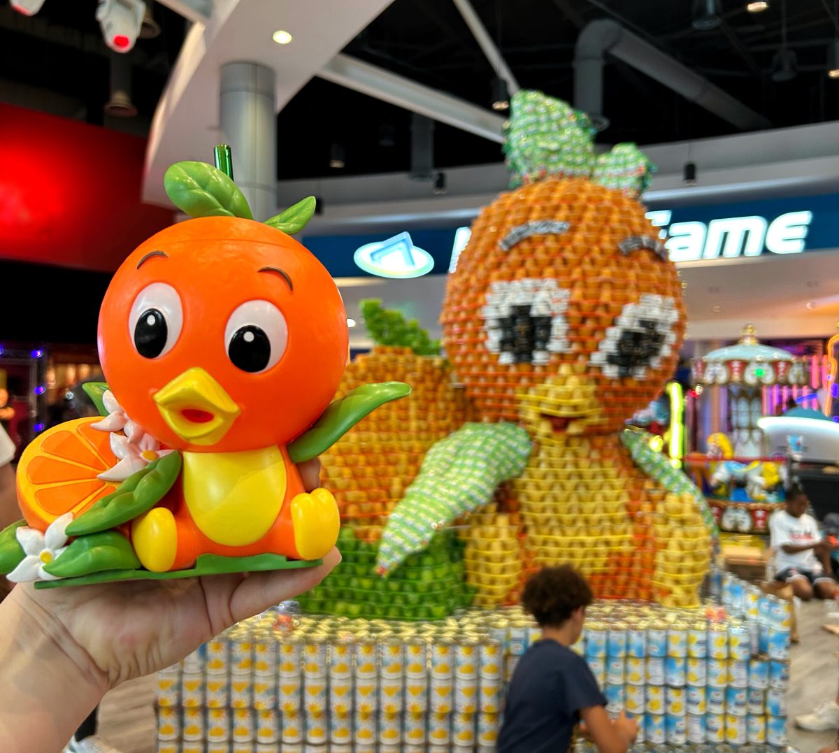 orange bird sipper held in front of canstruction orlando project