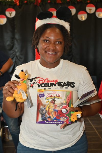 Woman with Disney VoluntEARS shirt poses with toys
