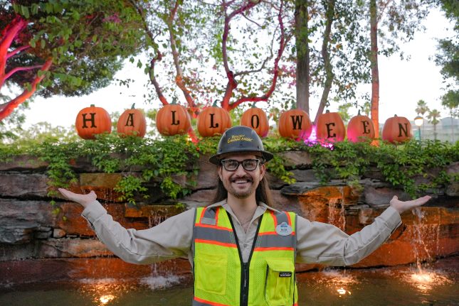 Resort Enhancement cast member Nick Stauf happily poses with pumpkins on display in the Downtown Disney District.