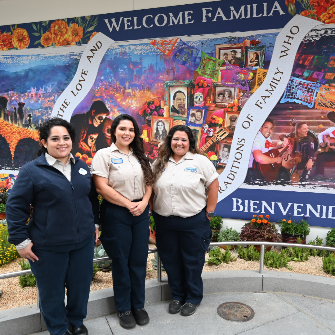 Designer and artists Danielle Lopez (left), Ashley Flores (center) and Ramona Garcia (right) stand in front of the Día de los Muertos mural “Love and Traditions” designed for Hispanic and Latin Heritage Month at Disneyland Resort.