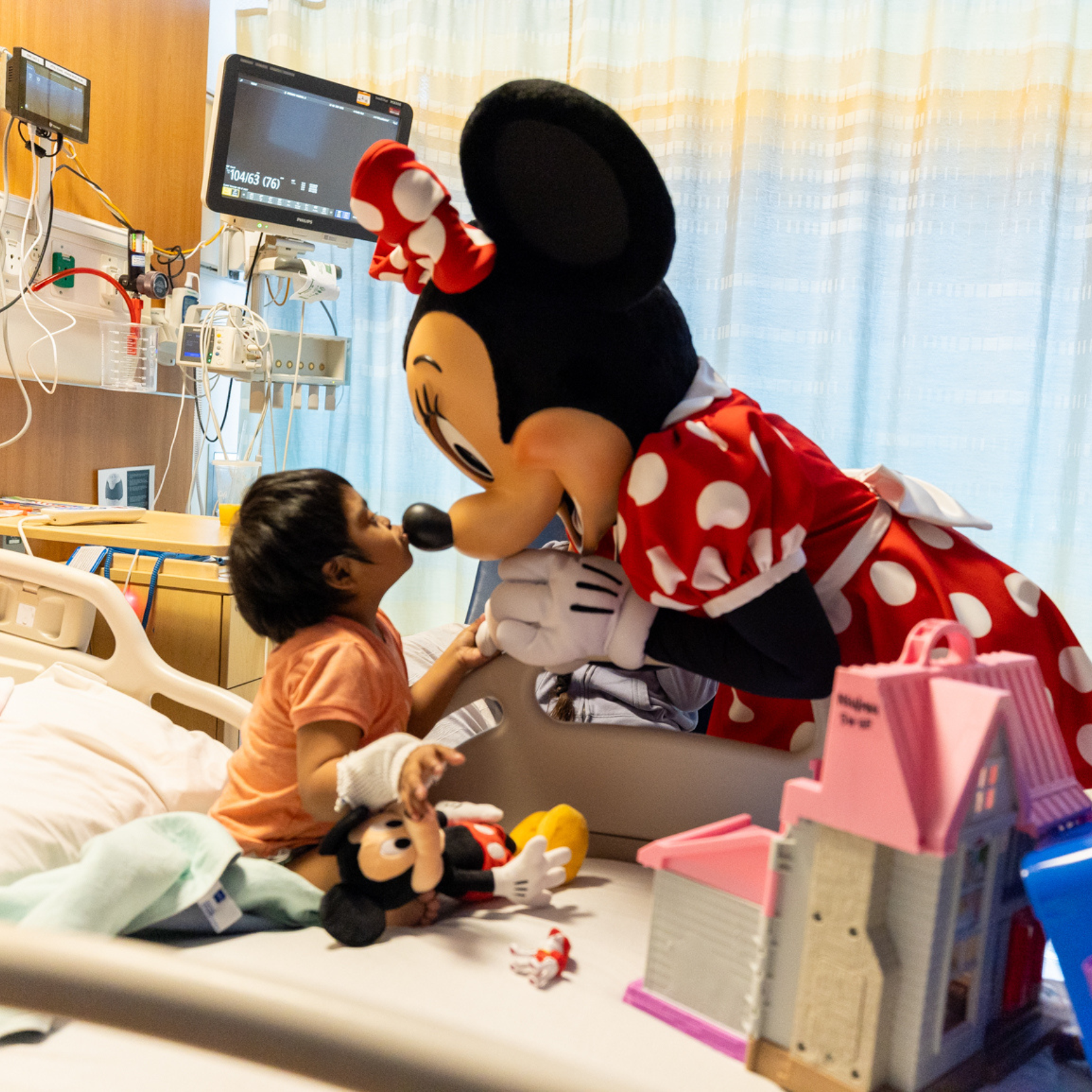 Minnie Mouse greets a child in a hospital bed at CHOC during a hospital visit.