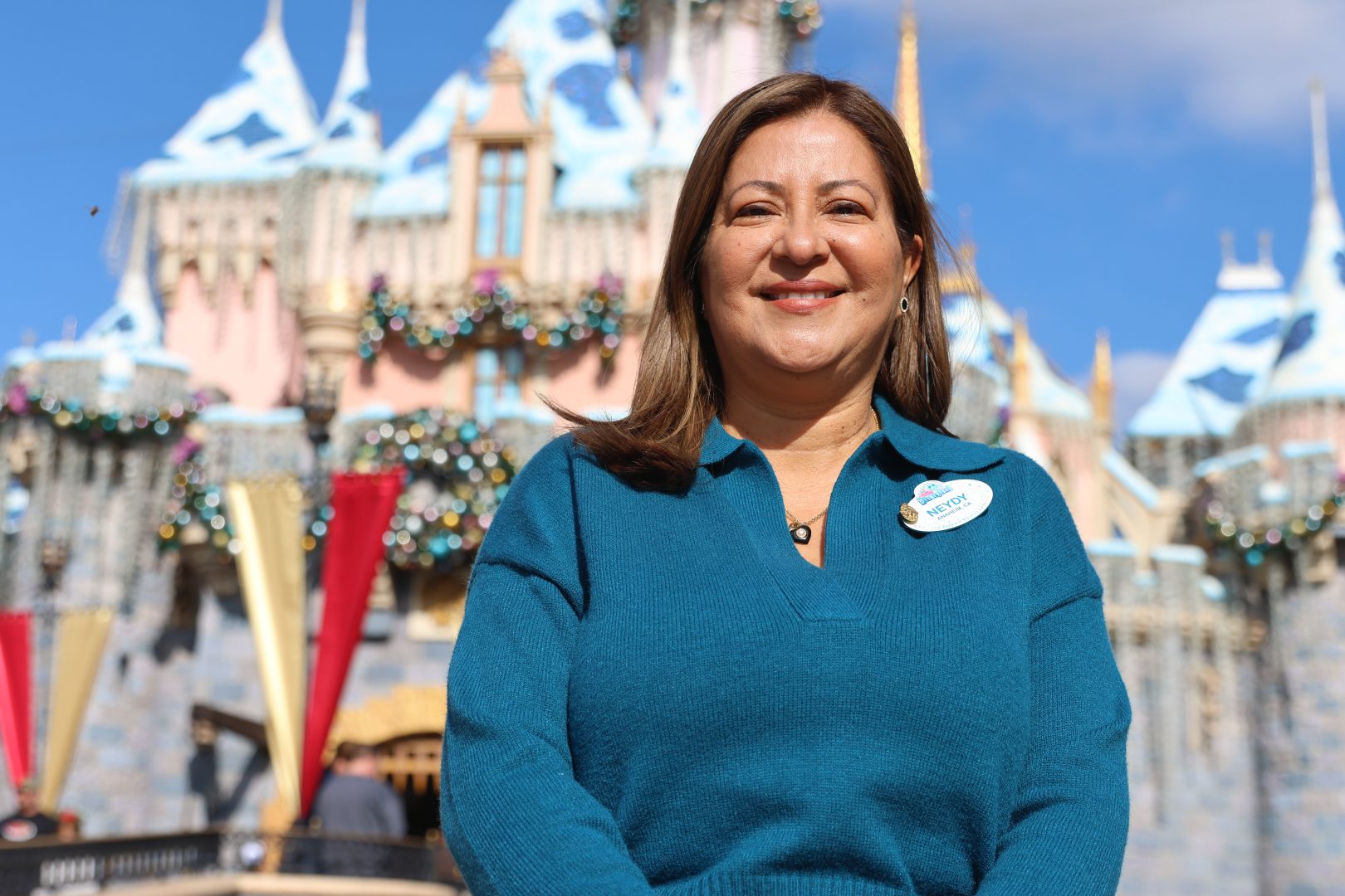 Neydy Bourges poses in front of the holiday decorated Sleeping Beauty Castle in Disneyland park.