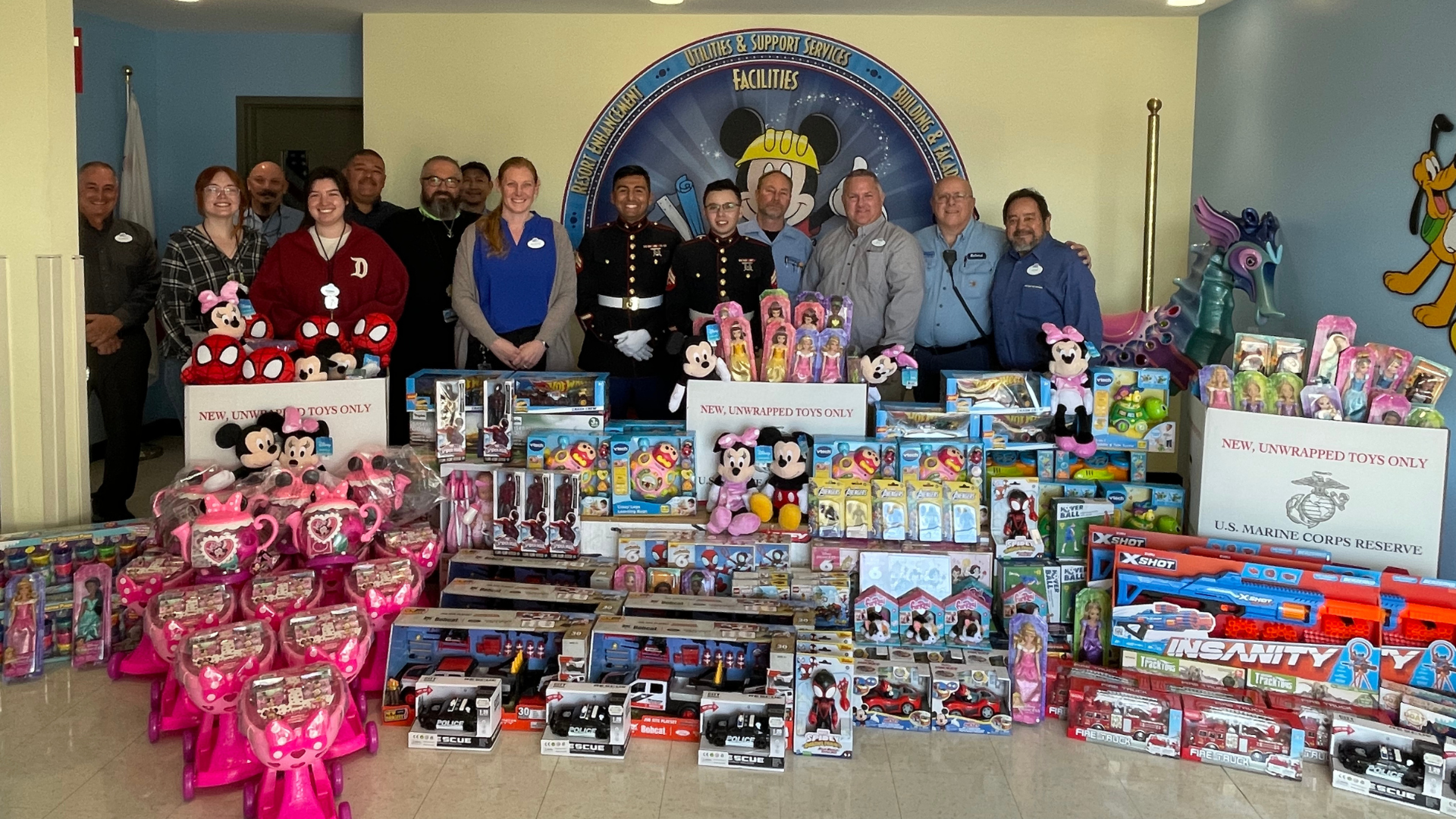 Cast at Cerritos Warehouse pose together for a photo in front of the 232 toys their team donated for Toys for Tots. 