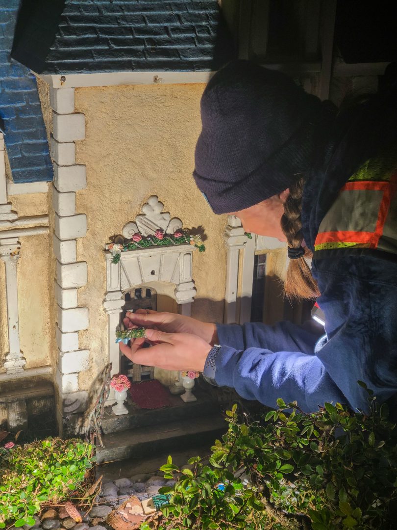 Resort Enhancement cast member, Ali Peale, installs a small wreath on Cinderella’s chateau in Storybook Land. 