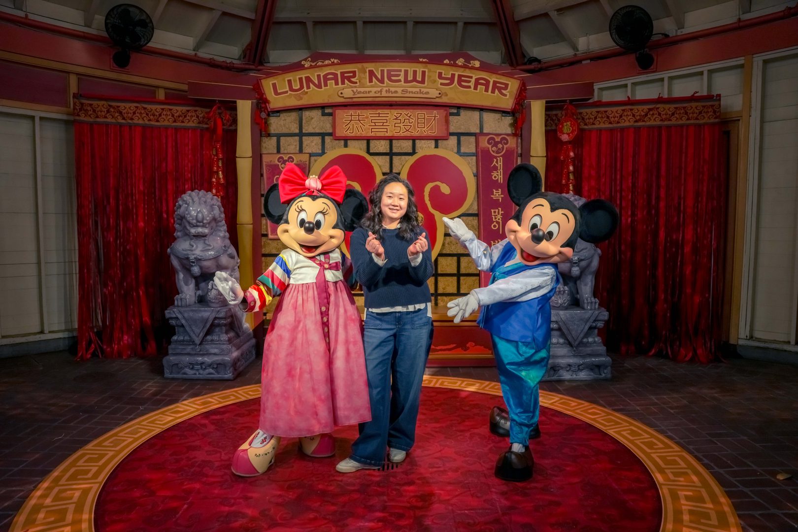 Cast member Grace Kang poses with Mickey Mouse and Minnie Mouse in their Lunar New Year costumes.