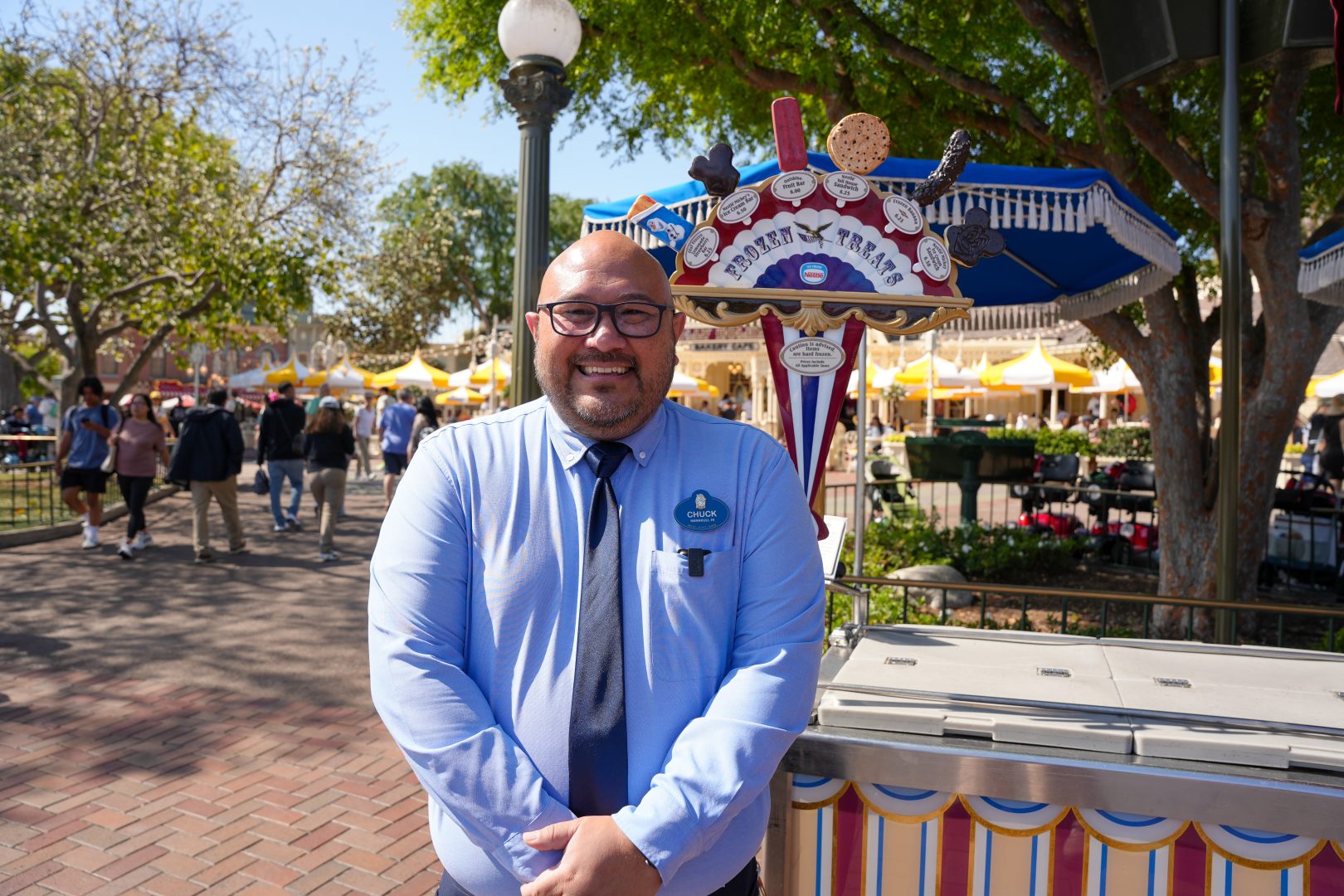 Chuck Garcia-Howell, an area manager of Outdoor Vending Food and Beverage, poses in front of an Outdoor Vending frozen treats cart in Disneyland park.