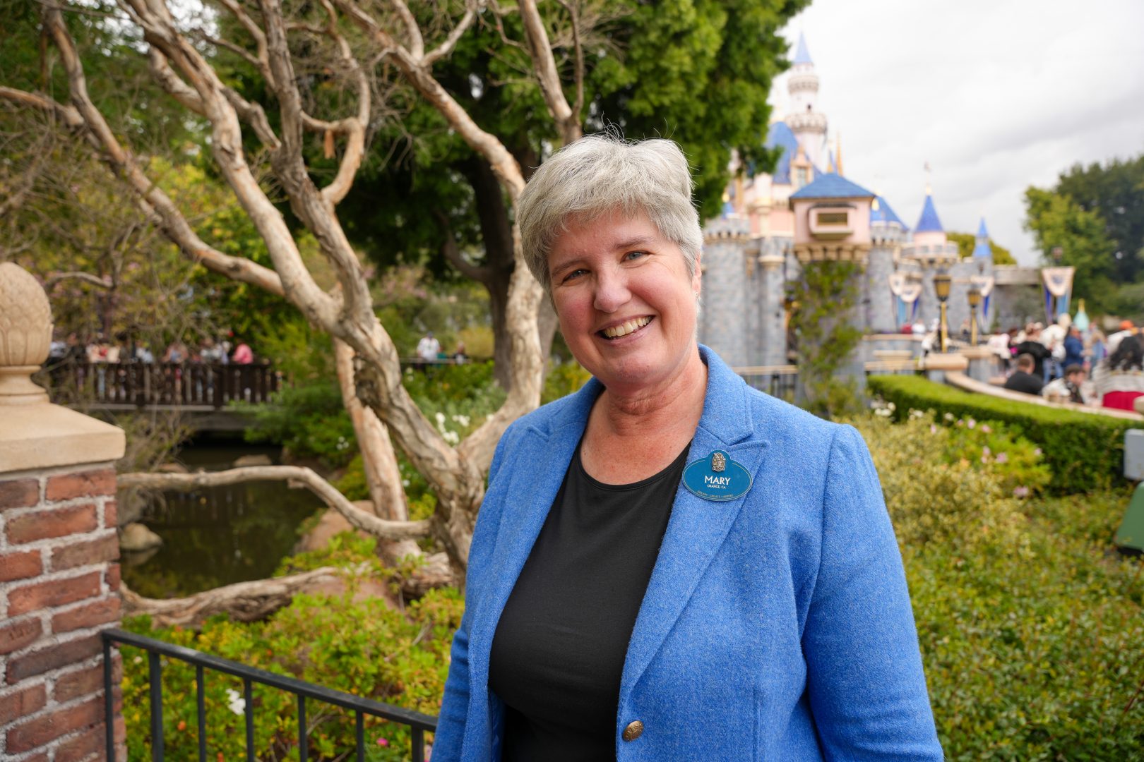 Senior Duty Manager Mary Cobb smiles by Sleeping Beauty Castle at Disneyland park.