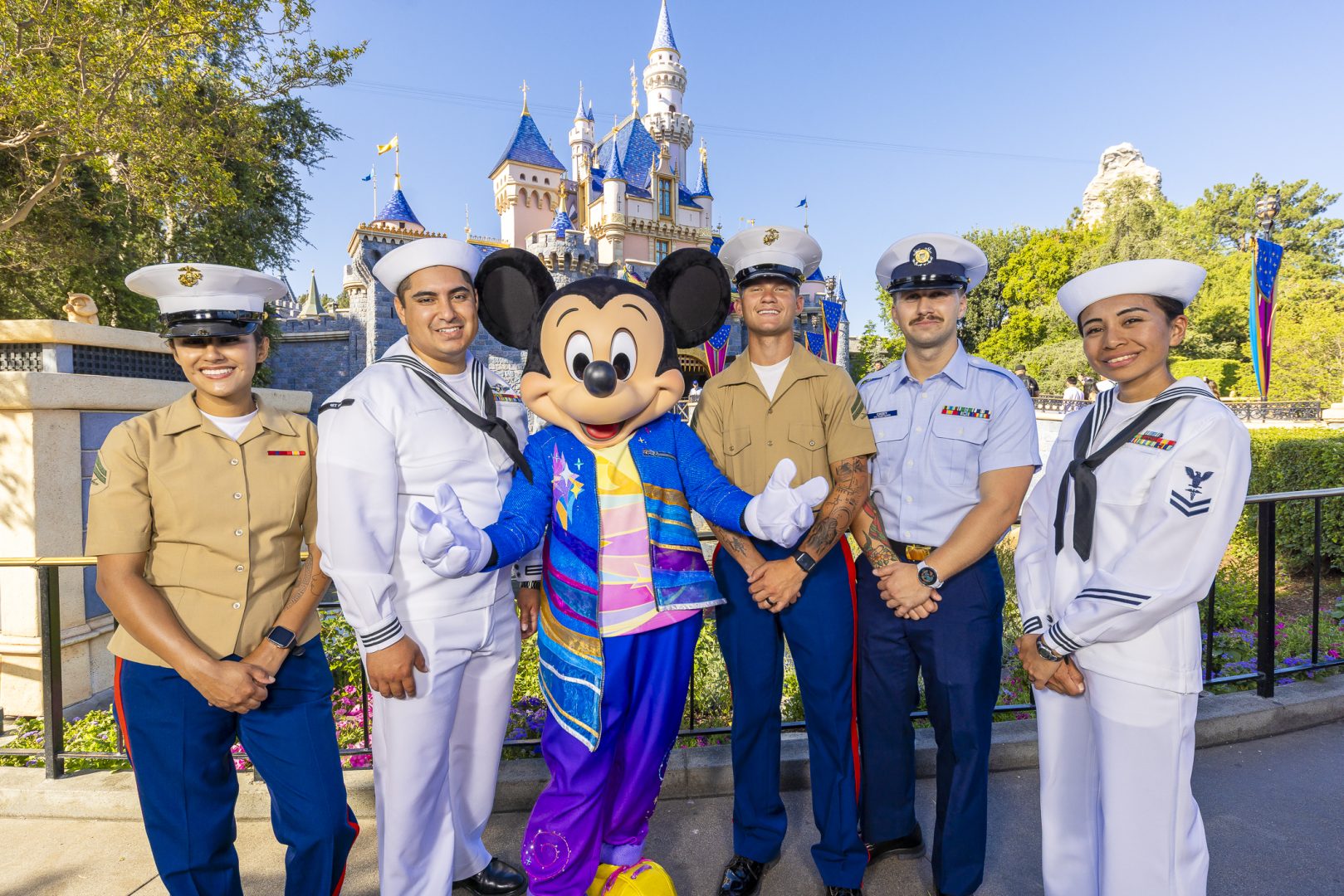 Service members smile with Mickey Mouse in his 70th Celebration attire.